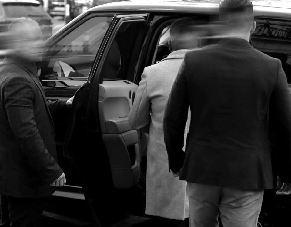 BPS close protection officers opening the rear door of a vehicle for a client at the kerb