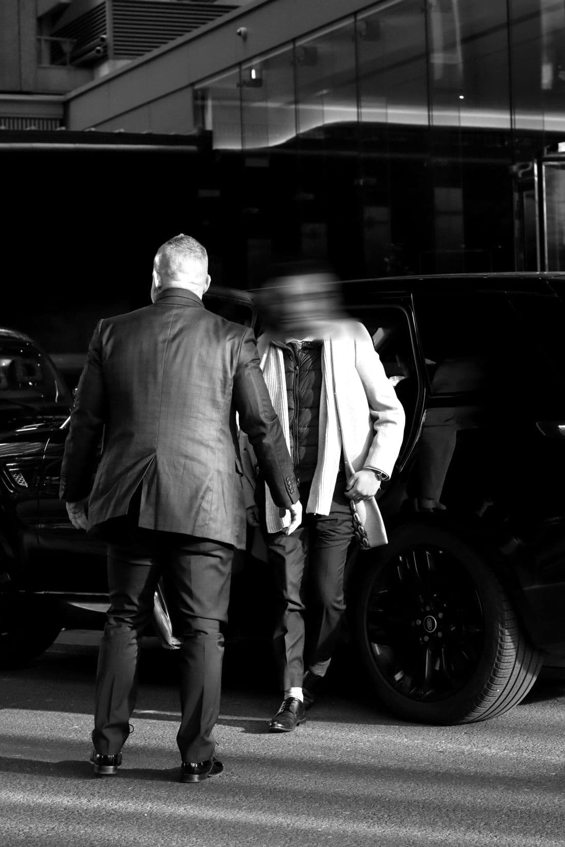 Two BPS officers walking a client from a waiting vehicle towards a building entrance
