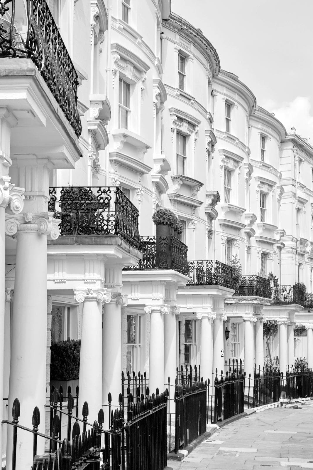 A curving London terrace of white stucco houses with columned porches and black iron balconies and railings