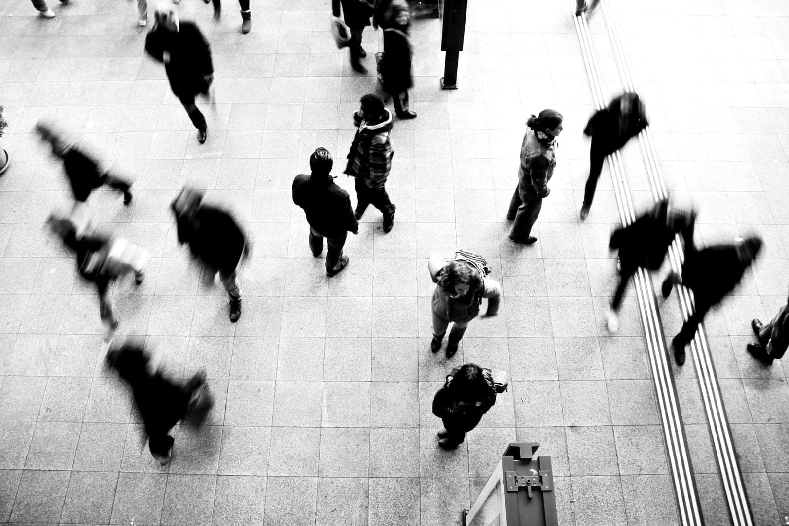 A concourse seen from above, people crossing it, some blurred by movement