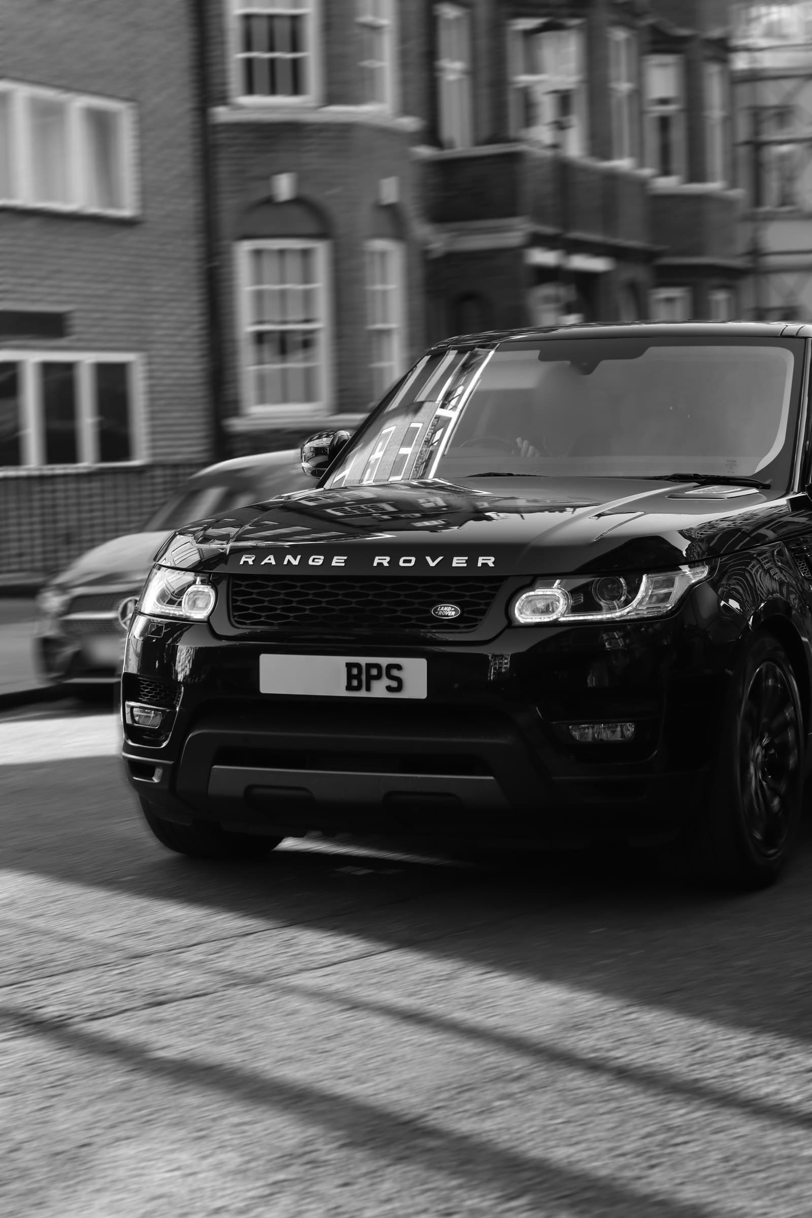 A black BPS Range Rover on the move along a street of brick mansion blocks, the background blurred by its speed