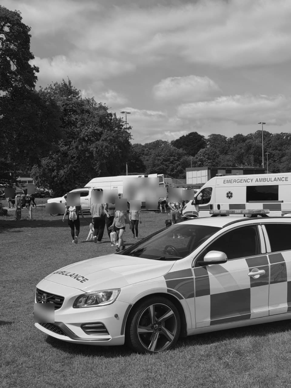 A rapid response car on the grass at an outdoor event, an emergency ambulance behind it