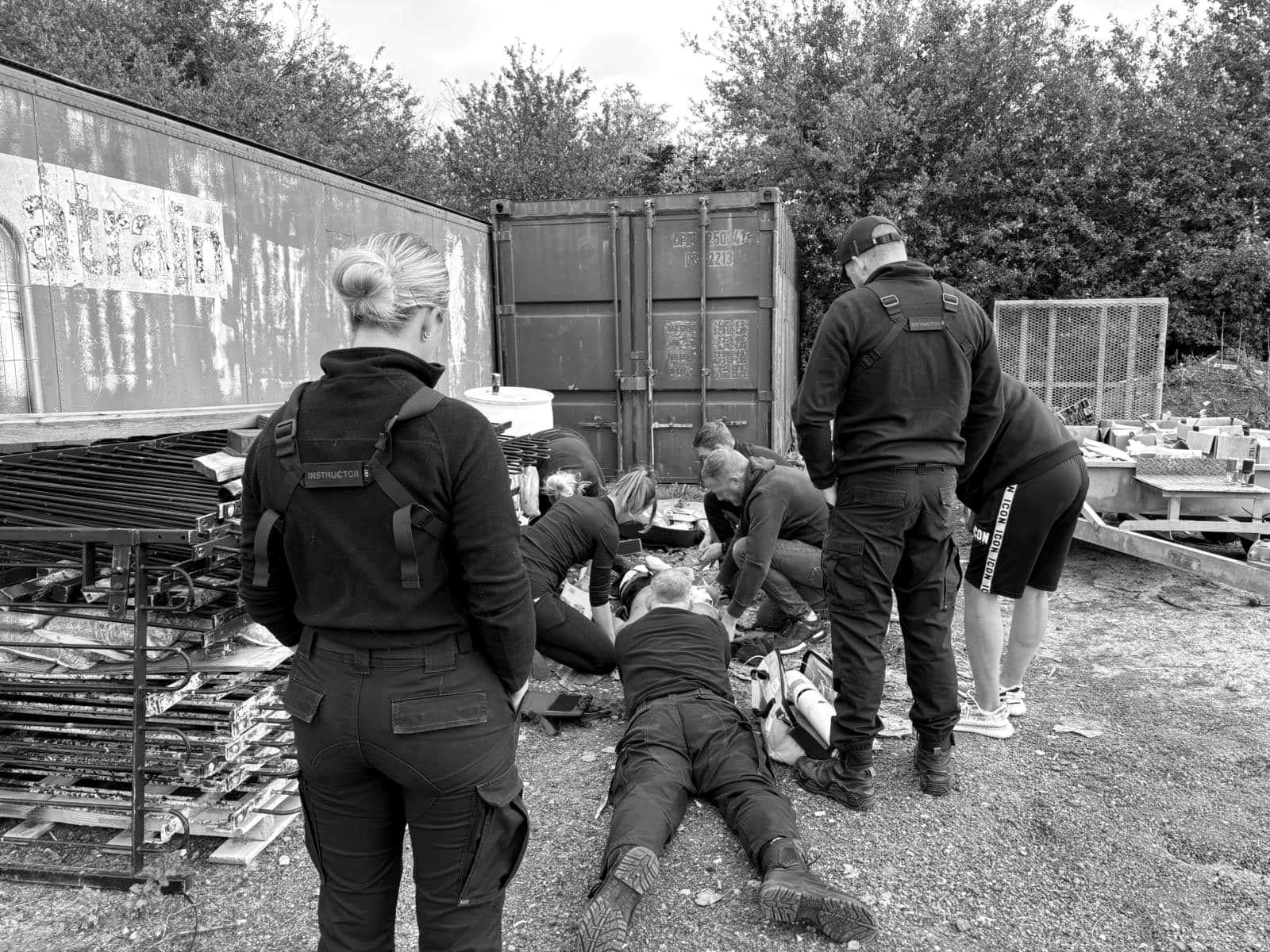 An outdoor casualty scenario on a BPS medical training course: course members treat a casualty on the ground while two instructors look on