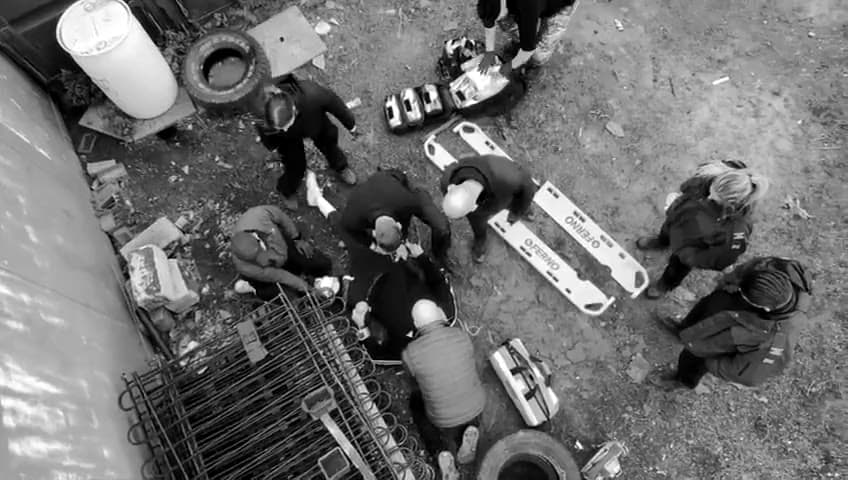 Seen from above: course members on a BPS medical training scenario treat a role-play casualty on the ground beside two scoop stretcher halves