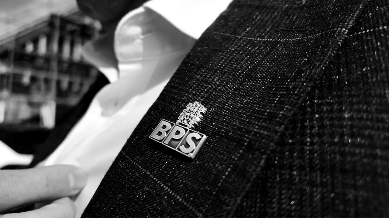 The BPS lapel pin on the jacket of a suited close protection officer